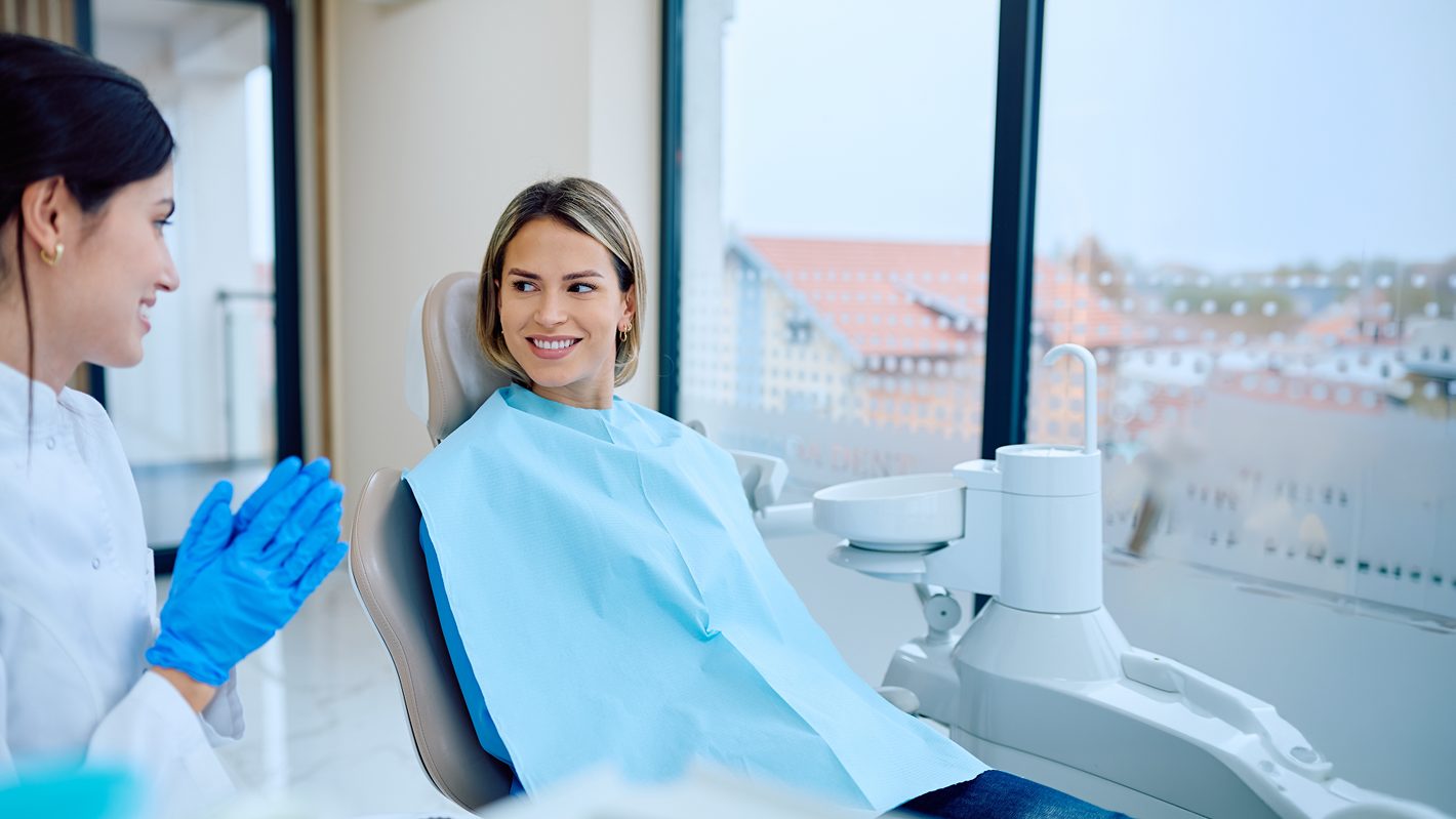 Dentist speaking with a smiling patient in the treatment room